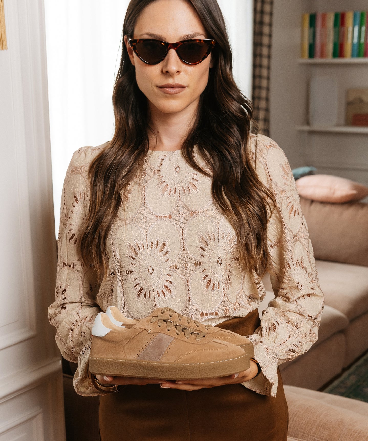 Femme en chemisier en dentelle tenant des sneakers vintage en daim camel – LYNXA KOST